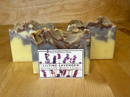 Three bars of lilting lavender soap with a label on a wooden surface