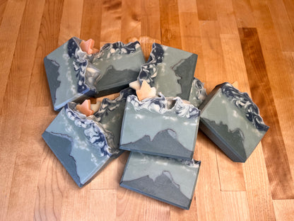 Set of handmade soap bars with mountain and cloud design on a wooden surface