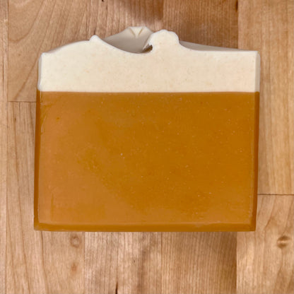 Bar of soap with a brown base and white top on a wooden surface