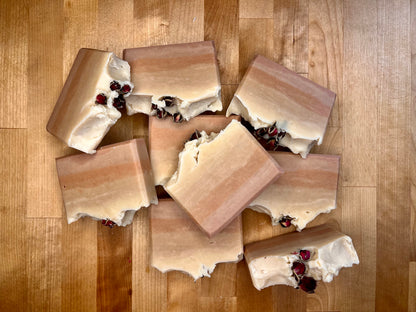 Pink layered soap with dried rose buds on top; sitting on a wooden surface