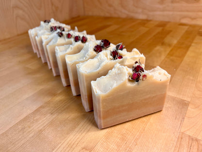 Row of handmade soap bars with rose buds on a wooden surface