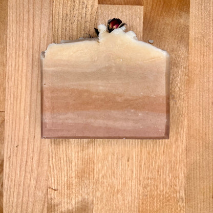 Single bar of pink and white Rebel Rose Soap on a wooden surface