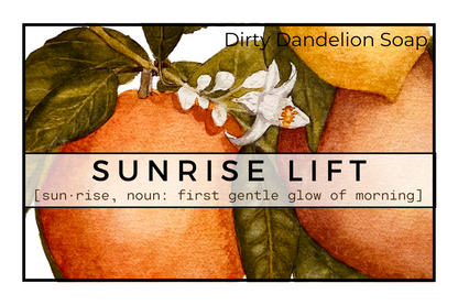 Watercolor label for Sunrise Lift featuring oranges, green leaves, and white blossoms, with the text Dirty Dandelion Soap and Sunrise Lift described as the first gentle glow of morning