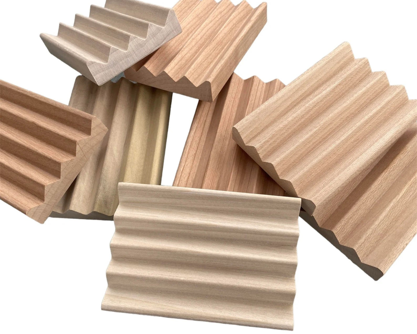 Assorted handcrafted wooden soap dishes with ridged grooves, shown overlapping in a fan arrangement, made from light to medium-toned natural wood and designed to allow soap to drain and dry between uses